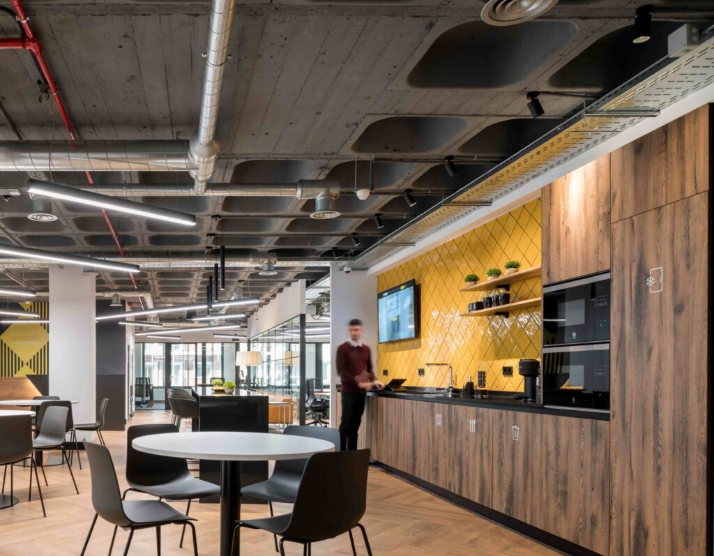 Empleado trabajando en la zona de comedor de una oficina, reflejando cómo un buen espacio impacta en la productividad, un factor clave en los costes ocultos de una mudanza.