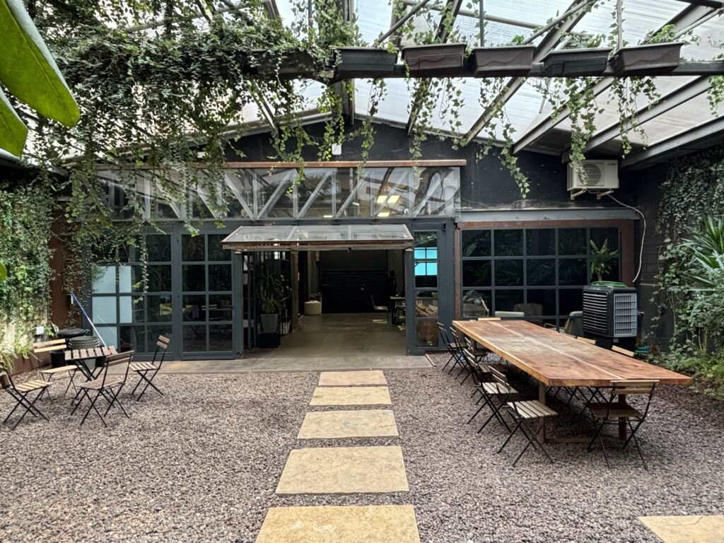 Patio exterior con vegetación en unas oficinas para startups, un ejemplo de las amenidades que mejoran el bienestar del equipo y atraen talento.