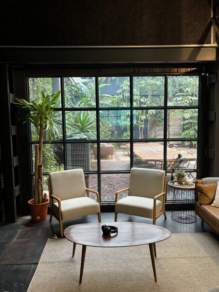 Zona de descanso con sillones cómodos y vistas a un jardín, reflejando cómo el diseño de las oficinas para startups impacta en la cultura de empresa.