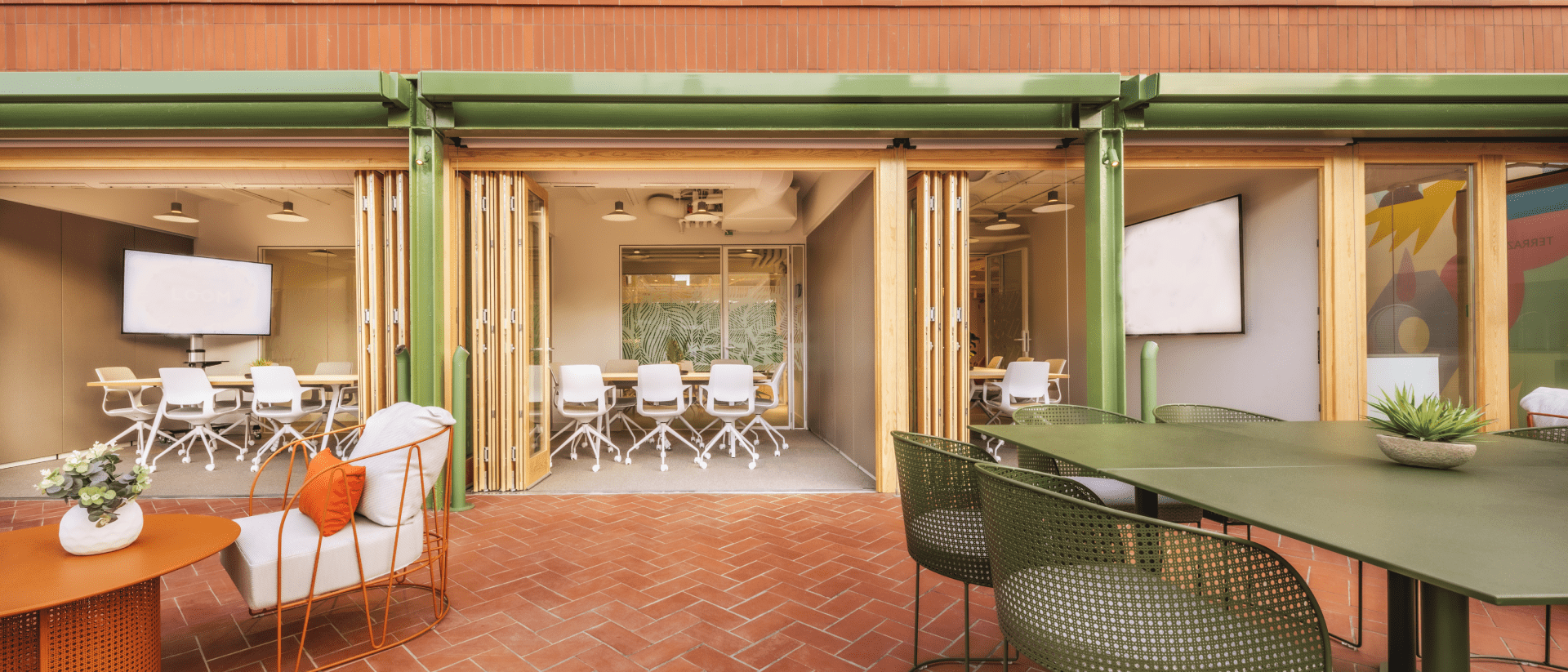 Salas de reuniones de una oficina flexible con puertas plegables abiertas a una terraza, ejemplo de planificación de espacio para startups en crecimiento.